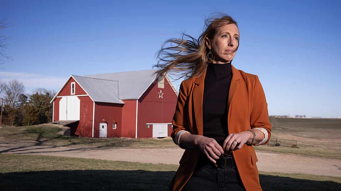 A woman stands near a farmhouse