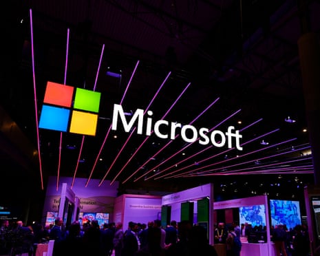 A colourful Microsoft logo hangs above a crowded Mobile World Congress exhibition hall with neon lights
