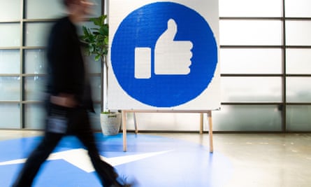 Facebook’s headquarters in Menlo Park, California - person walks by large thumbs-up sign