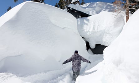 A homeowner is dwarfed by a huge winter snowfall in Mammoth Lakes, California, in March 2023.
