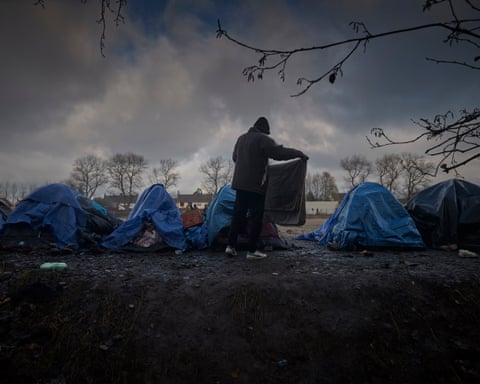 A refugee folds his blanket at a migrant camp