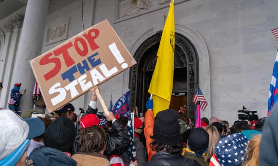 A member of the Capitol attack mob holds a ‘Stop the Steal’ sign on 6 January.
