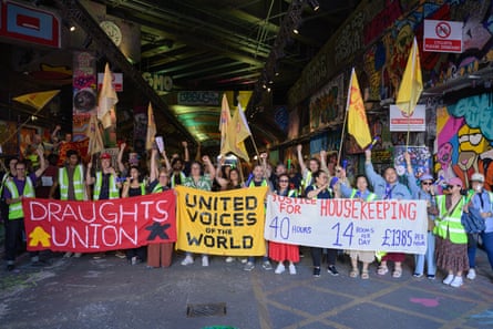 People wave flags and hold banners under a tunnel in Waterloo