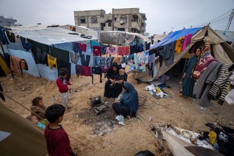 Palestinians displaced by the Israeli bombardment of the Gaza Strip make tea at the makeshift tent camp in the Muwasi area.