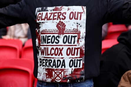 A Manchester United supporter shows off a jumper protesting against the club's owners and executives