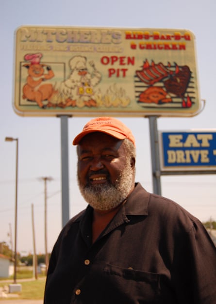 man smiles under sign for business
