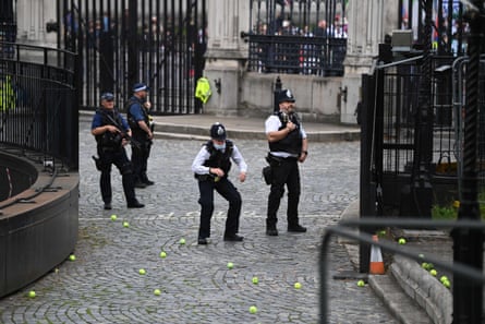 A policeman ducks as protestors throw tennis balls over fences around the Houses of Parliament.