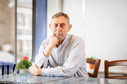 Michael Rosen sitting at a cafe table with his chin resting on his raised fist.