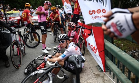 Tadej Pogacar sits on the road while the 14th stage of the Tour de France is neutralized after an early crash.