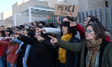 A line of women all pointing an accusatory fin ger at someone off camera. One is holding a sign reading ‘Merci, Gisèle’