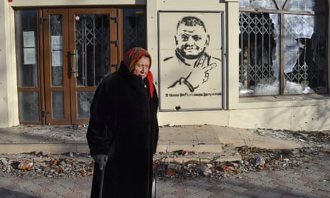 An elderly woman walks along a street against background of a graffiti depicting General Valery Zaluzhny, head of Ukraine's armed forces and writing "God is with us and commander Zaluzhny" in Bakhmut, Ukraine.