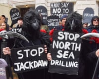 Climate activists in crow masks hold signs reading "Stop Jackdaw" and "Stop North Sea Drilling"