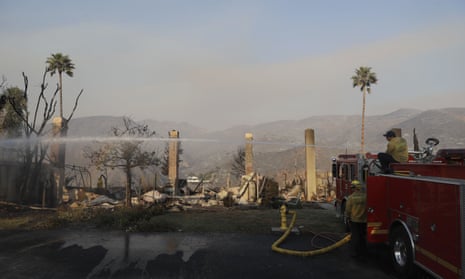 Firefighters hose down hot spots on a wildfire-ravaged property in Malibu, California.