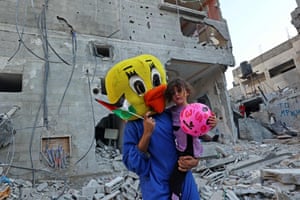 Rafah, Gaza Strip. A Palestinian clown carries a child during a show in the rubble of a building destroyed in the latest round of fighting between Israel and Palestinian militants