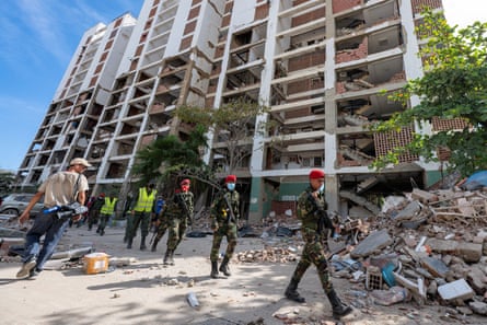 Venezuelan Bolivarian Army soldiers walk in front of a damaged building in La Guaira state.