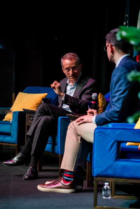 A man speaking to another on a stage.