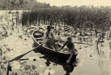 Two people gather water lilies from a rowing boat