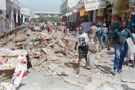 People walk along a street in Port-au-Prince where rubbish is piled up