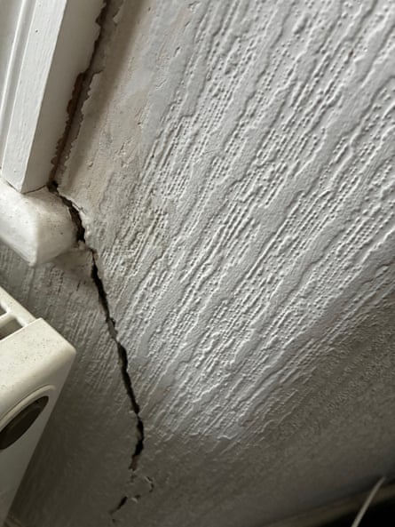 A deep, diagonal crack next in a wall next to a window