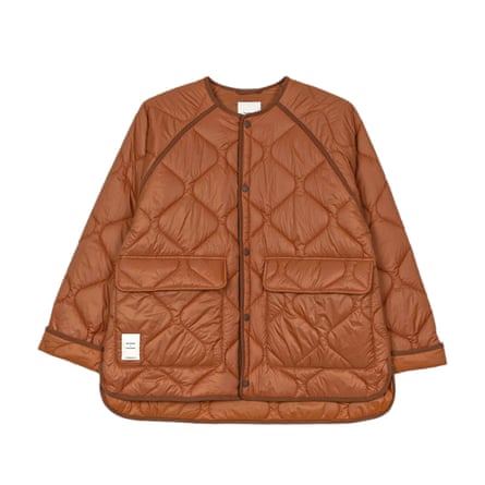 A burnt orange quilted collarless jacket on a white background