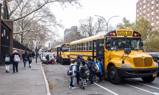 Students wearing masks board a school bus outside New Explorations into Science, Technology and Math (NEST+m) school on the Lower East Side neighborhood of Manhattan on Tuesday, Dec. 21, 2021, in New York. (AP Photo/Brittainy Newman)