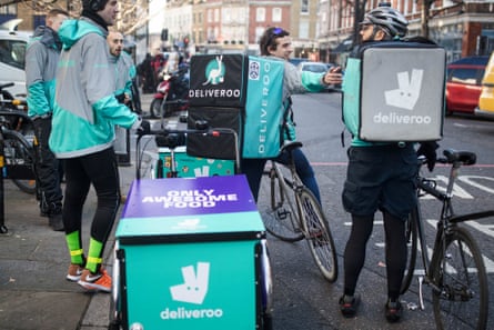 Deliveroo cycle couriers wait for orders on a London street.