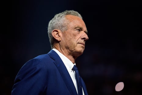 A man who is Robert F Kennedy Jr looks stern and wears a blue suit and tie