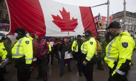 Police are followed by yelling protesters as they attempt to hand out a notices to protesters in Ottawa, on Thursday, Feb. 17, 2022. Hundreds of truckers clogging the streets of Canada's capital city in a protest against COVID-19 restrictions are bracing for a possible police crackdown. (Justin Tang /The Canadian Press via AP)