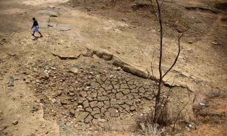 An Indian farmer walks across the bed of a pond that has dried out during a water crisis.