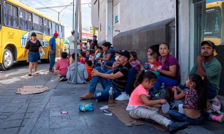 Migrants, mostly from Mexico, are pictured sitting on the ground waiting near the Paso del Norte Bridge at the Mexico-US border, in Ciudad Juarez, Mexico, on 12 September.