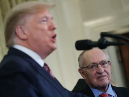 A man wearing a suit, left, speaks as the other man, right, looks at him.