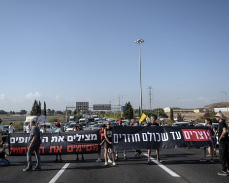 Israeli protesters hold banners and block the 4th Avenue during the demonstration.
