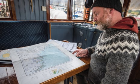 Sigurdur Jonsson looks at maps on his boat, the Aurora.