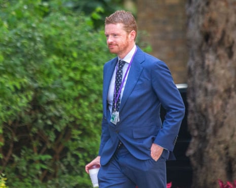 He wears blue suit and Downing Street pass round his neck