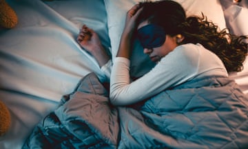 a woman wears a sleeping mask in bed