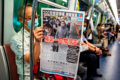 A Hong Kong commuter reads a copy of the Apple Daily newspaper in August 2020 that covers the arrest of its founder, Jimmy Lai.