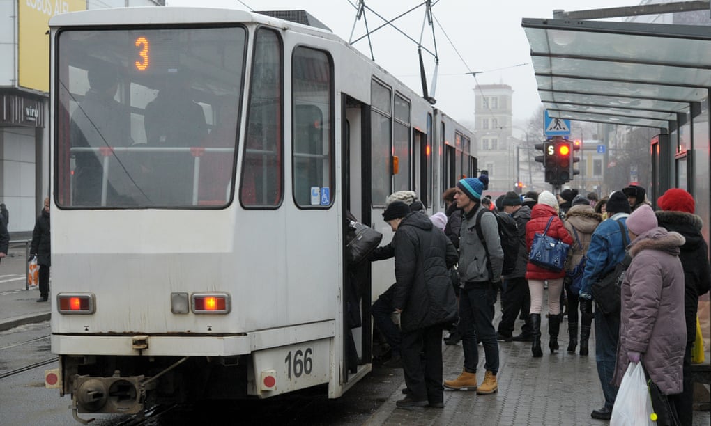 Passengers board a public transport tram at a stop in downtown Tallinn