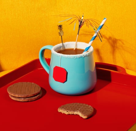 A mug of tea, with a sparkler, straw and cocktail decoration in it and salt around the end of the mug, on a tray with biscuits on it