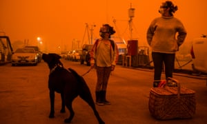 Eden residents prepare to take shelter onboard a tugboat at the town’s wharf, rather than evacuating north by road, as the so-called border fire threatened the town on Sunday.