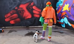 A woman looks at a street artwork featuring a red face by Philaicio at Yardworks, a festival in Glasgow.