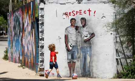 A boy plays with a ball next to a mural in Barcelona of Lamine Yamal and his fellow winger Nico Williams.
