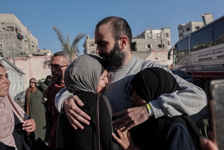 A man embraces two women in head scarves