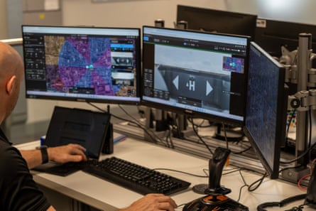 Man sat at desk with keyboard and three computer screens in front of him
