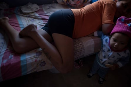 A woman lies on a bed next to her baby