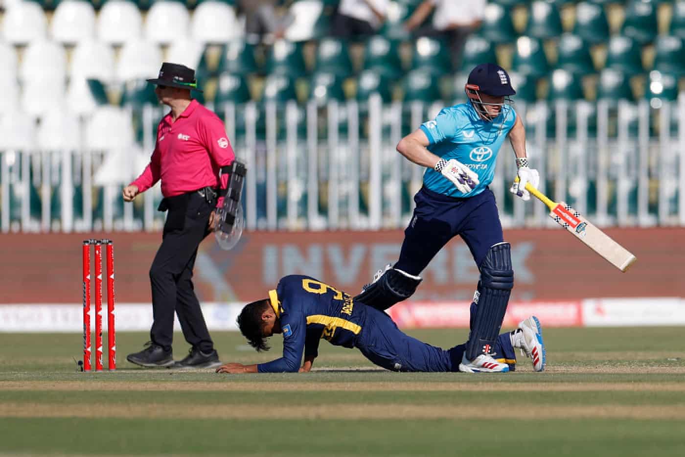 England's Harry Brook runs past fallen Sri Lankan fielder Dunith Wellalage during a match