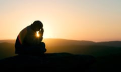 A praying man sat on a hill at sunrise