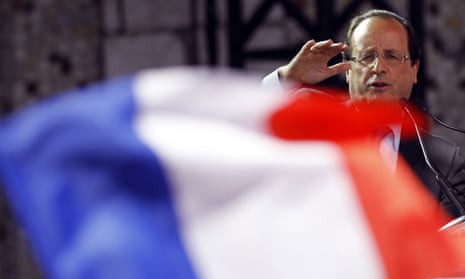 A French flag flutters in the foreground as Francois Hollande delivers a speech