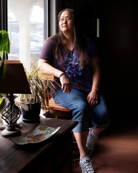 A woman sits at home and looks at a scrapbook of childhood photos