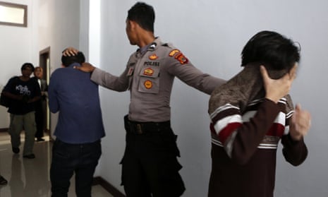 Two men on trial for being in a same-sex relationship are escorted to the courtroom at the Sharia court in Banda Aceh, Indonesia. Police in Jakarta have now arrested 141 men for a party at an alleged gay sauna.