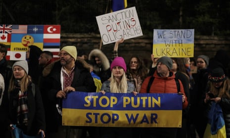 people hold sign that says 'stop putin, stop war' on blue and yellow background, colors of Ukraine flag